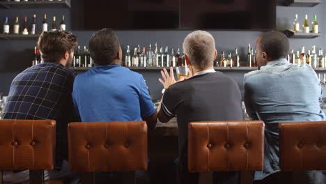 rear view of male friends watching game in sports bar