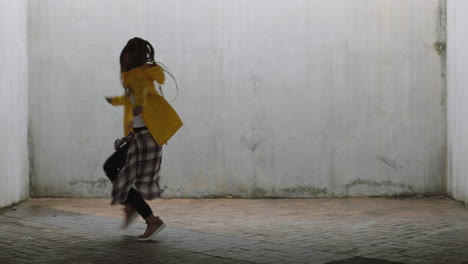 Mujer-Bailando-Joven-Bailarina-Callejera-De-Raza-Mixta-Realizando-Movimientos-De-Hip-Hop-De-Estilo-Libre-Disfrutando-De-La-Expresión-De-Danza-Moderna-Practicando-En-Un-Almacén-Sucio-Con-Chaqueta-Amarilla