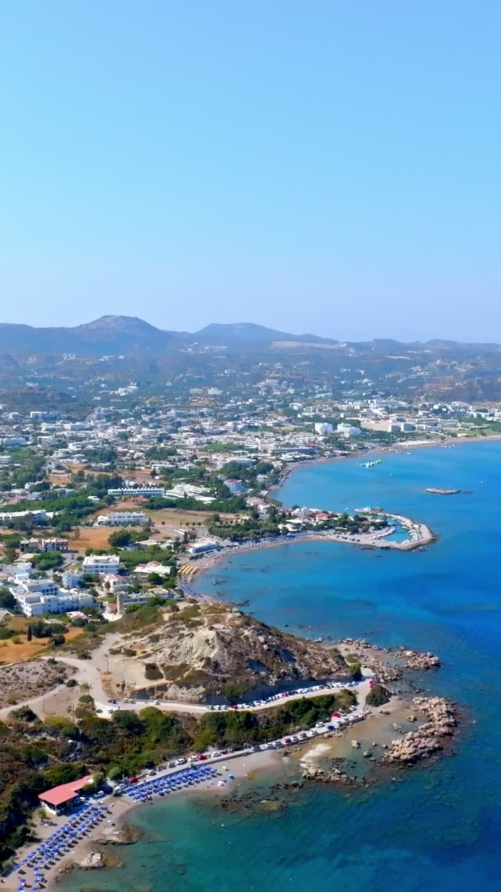 Vertical drone shot backwards over the coastline of Faliraki, sunny day in Rhodes