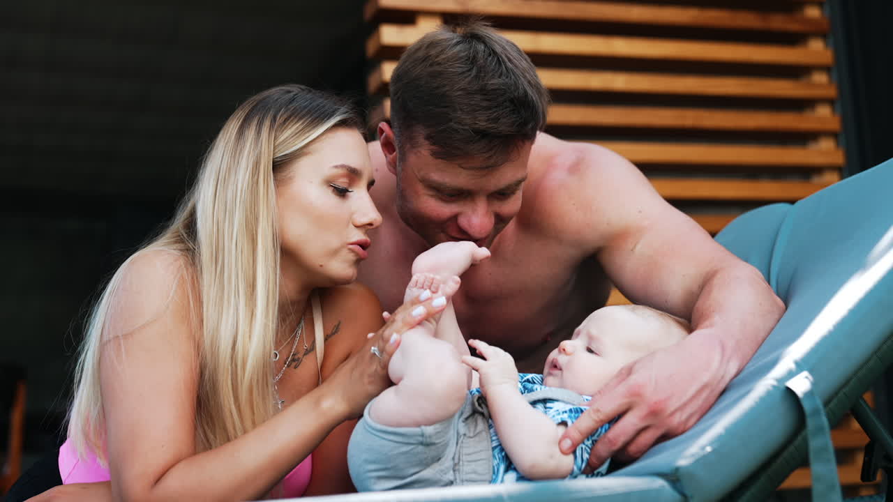 Cute Caucasian baby boy lies on the deck chair surrounded by loving parents. Family of three on vacation.
