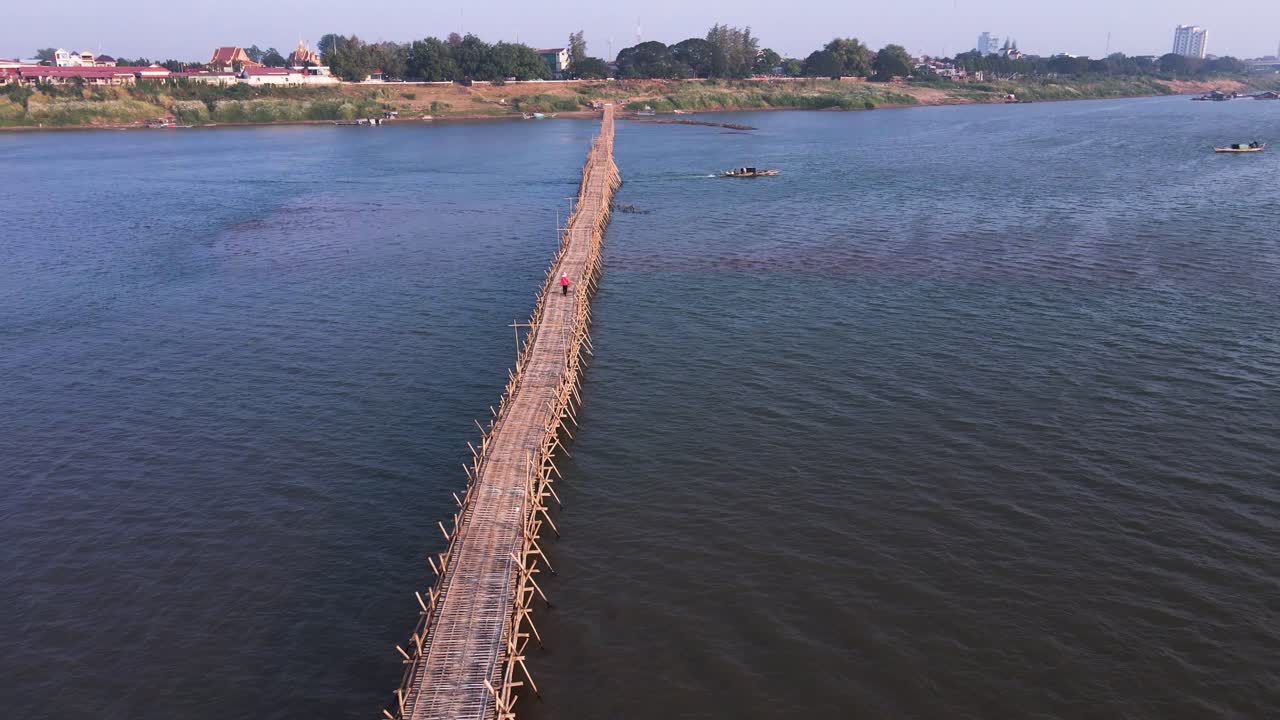 puente de bambú de madera natural con un barco que pasa sobre el río mekong en kampong cham, camboya - sobrevuelo aéreo de drones