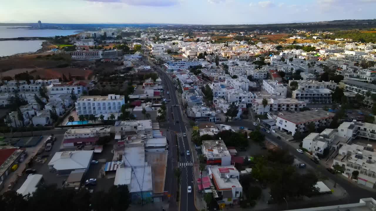 Vista aerea con drone di una città costiera con edifici bianchi, strade e un quartiere urbano vicino al litorale lungo il Mar Egeo, che crea un suggestivo paesaggio urbano mediterraneo in Grecia.