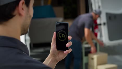 Rear-view-of-delivery-man-holding-mobile-with-mobile-app