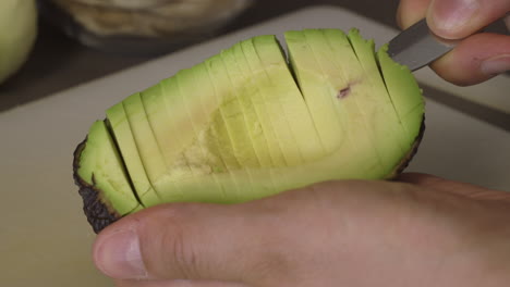 removing sliced avocado from its peel with a spoon - closeup shot