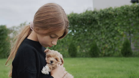 cute little girl sitting in the park with a puppy in her arms. side view