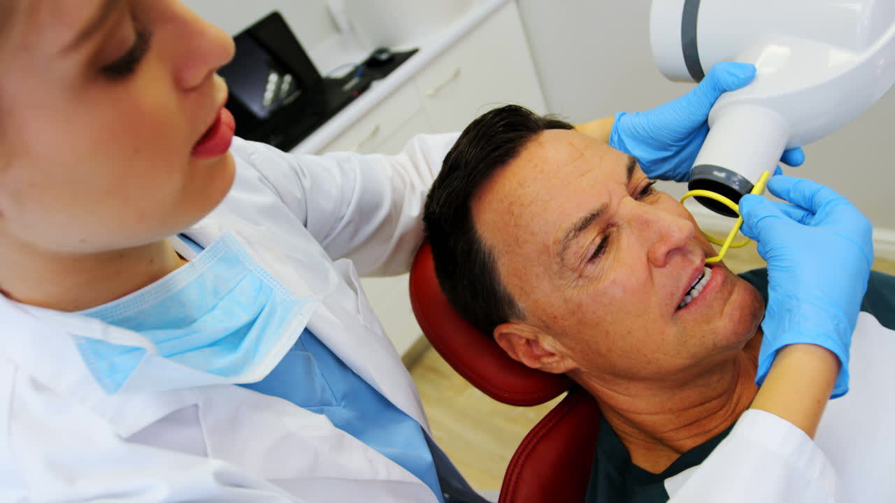 Dentista che esamina un paziente maschio con lo strumento
