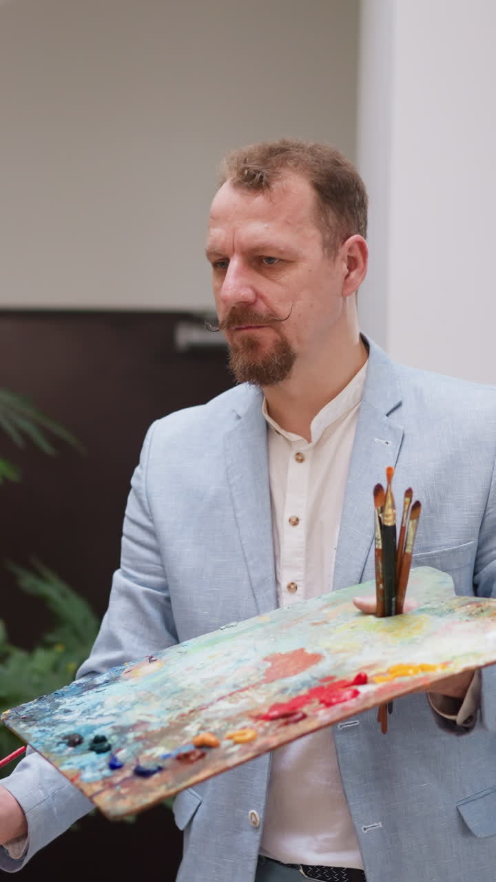 아티스트는 스튜디오에서 오일 페인트로 그림을 만니다. 진지한 사람은 작업장에서 캔버스에 다른 페인트를 적용합니다. 분위기를 개선하기위한 예술적 취미