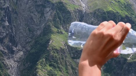 a teenager drinks a bottle of water in the alps to dehydrate during a hike in the mountains , switzerland, obwalden