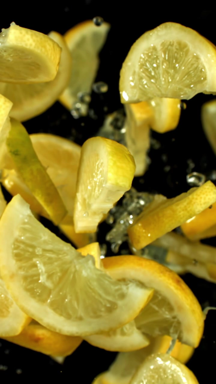 Fette di limone fresche che cadono con schizzi d'acqua al rallentatore