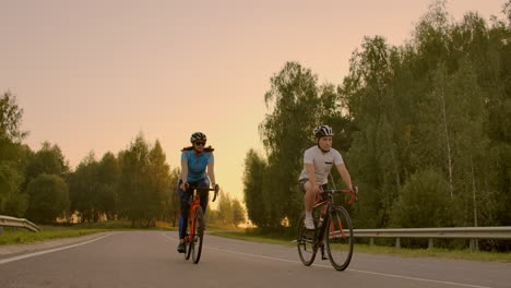 Empty-Space.-Sporty-friends-on-bicycle-on-sunset.-Couple-cyclist-go-along-coast.-Sport-in-Nature-background.-Group-of-people-two-road-biker-in-sunset.