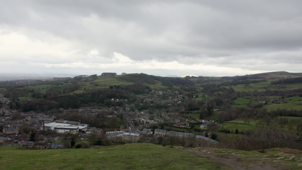 una vista del pueblo de bollington en el distrito de los picos en inglaterra desde la cima de una colina con colinas en la distancia