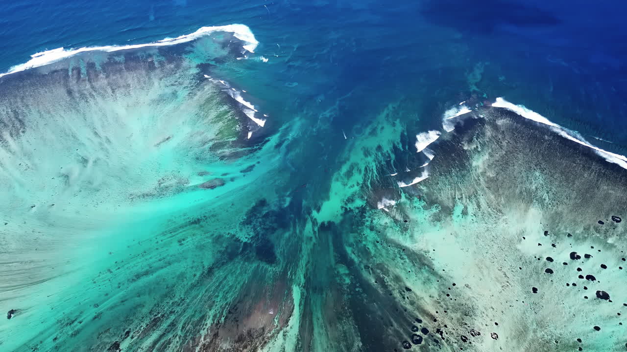 Vista aerea con drone delle acque turchesi della laguna e delle formazioni di barriera corallina a Mauritius, con onde che si infrangono lungo la linea della barriera corallina nell'Oceano Indiano.