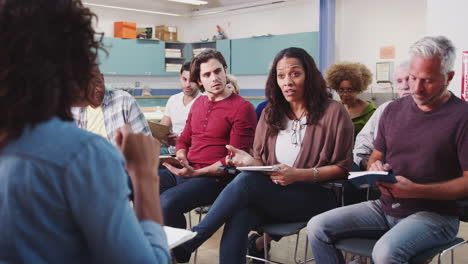 Group-Making-Notes-Whilst-Attending-Neighborhood-Meeting-In-Community-Center