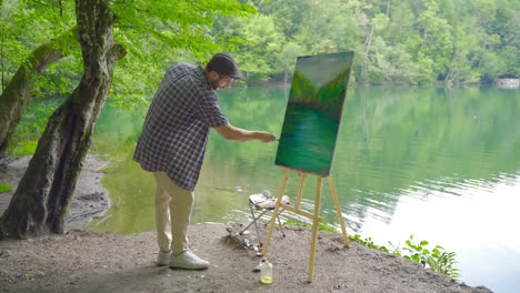 Cheerful painter paints on his canvas.