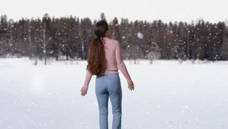 mujer joven al aire libre en un paseo viendo la nieve caer en el campo con el bosque