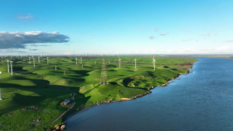 aerial view of montezuma hills wind turbine farm with electric power lines along sacramento-san joaquin delta river, california