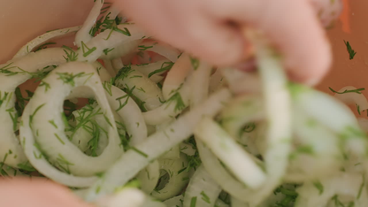 Mix sensoriale ravvicinato di aneto e cipolla da campeggio, primo piano sulle mani che separano delicati anelli di cipolla ricoperti di aneto tritato in una ciotola, consistenza umida, luce solare soffusa, scena intima di cucina da campo, tocco finale.