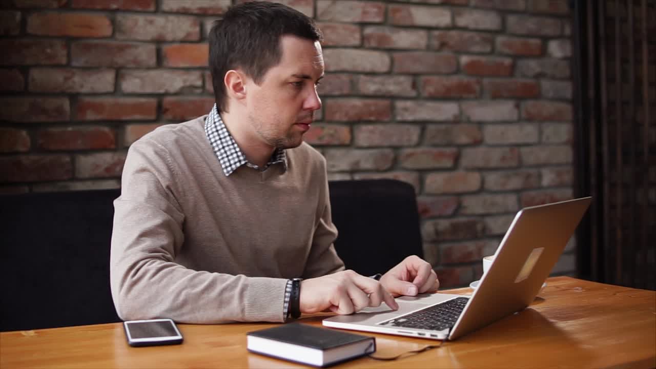 un hombre trabajando en una computadora portátil en un café