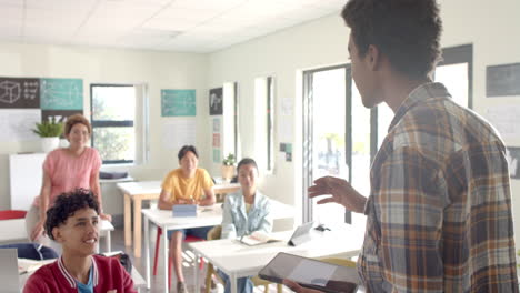 in high school, teenager presenting to classmates while holding book in classroom