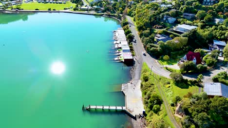 aerial footage captures akaroa's vibrant harbor, lush greenery, and rolling hills under bright sunlight, showcasing serene natural beauty
