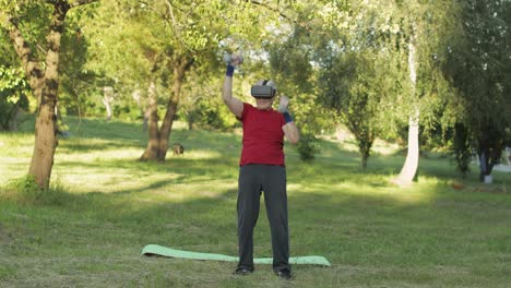 senior old grandfather man in vr headset helmet making fitness exercises with dumbbells in park