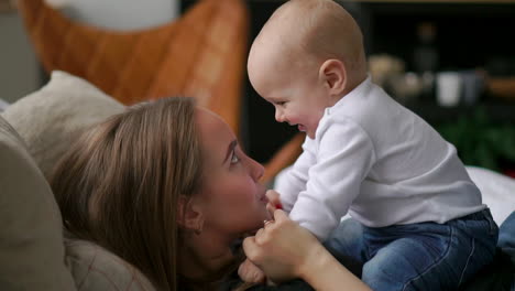 The-best-moments-from-life,-a-loving-happy-young-mother-hugs-a-nursing-son,-on-a-snow-white-blanket,-on-a-white-background.-concept-of-love,-family,-and-happiness-Concept:-children,-kids,-baby,-babies