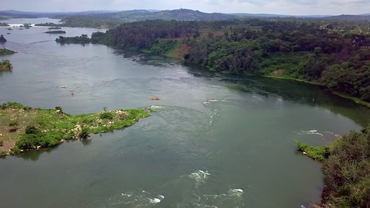Broad section of the River Nile in Uganda, captured from an elevated aerial view, several small rafting boats can be seen floating on the water’s surface, in an adventure experience