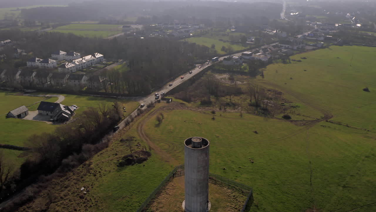 Aerial reverse dolly revealing the prominent water tower north of Clarinbridge, Galway.