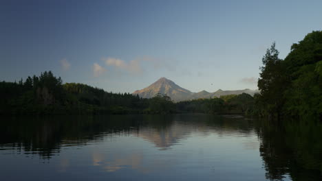 Serene-lake-side-view-with-distant-volcano-above-forest-canopy-line