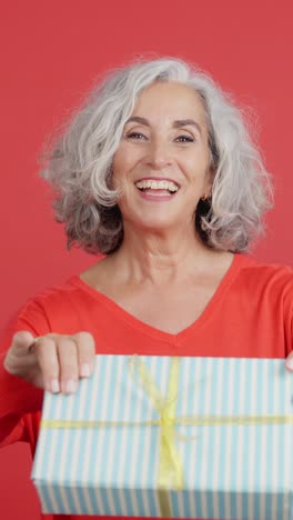 happy senior woman with grey hair holding a gift