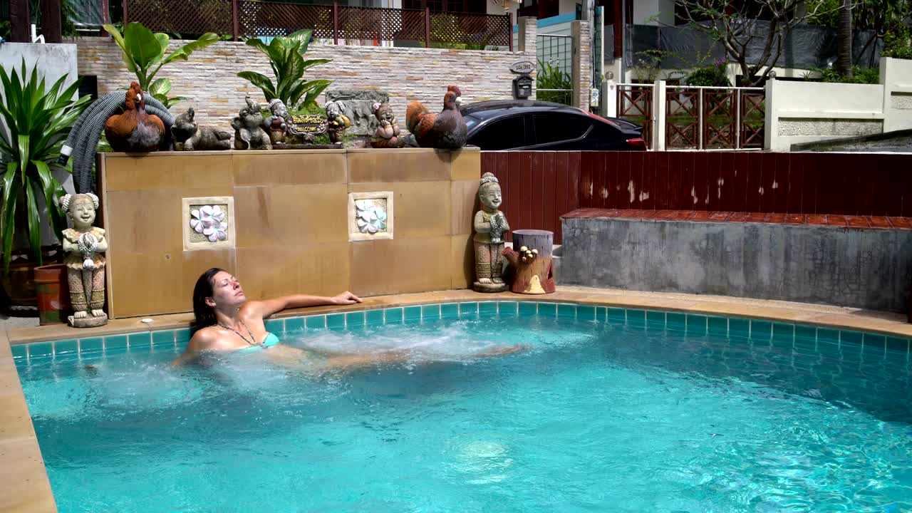 una mujer se sienta en la piscina con bañera de agua caliente