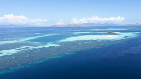 atolón de arrecife de coral de banco de arena paluau katangan al este en la isla de komodo indonesia con playa curva, toma aérea revelada