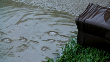 a steady flow of rain water flowing out of a gutter system during a tropical rain storm in california