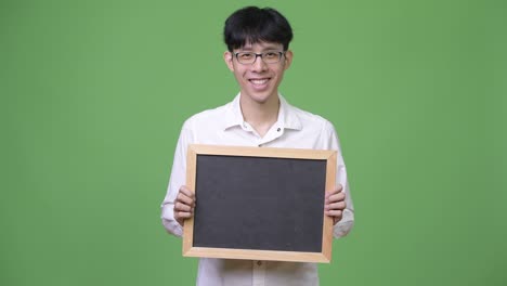 행복 한 젊은 아시아 사업가 는 블랙보드 를 들고 미소 짓고 있다