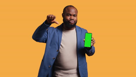 man showing thumbs down sign gesturing holding green screen phone