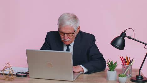 smiling mature business man sits at workplace office desk, opening laptop computer, start working