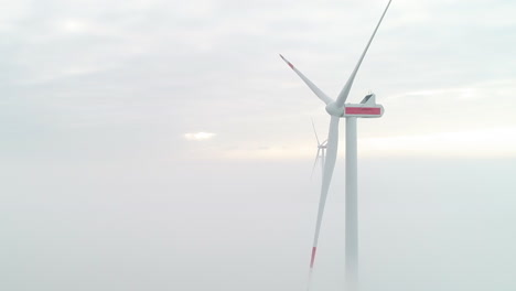 Luftaufnahme-Von-Windmühlenturbinen-über-Einer-Schicht-Aus-Dichtem-Nebel,-Die-Grüne,-Saubere-Energie-Erzeugen