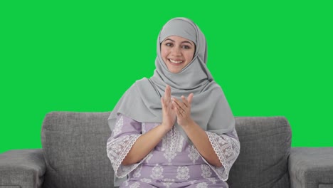 mujer musulmana feliz aplaudiendo y apreciando la pantalla verde