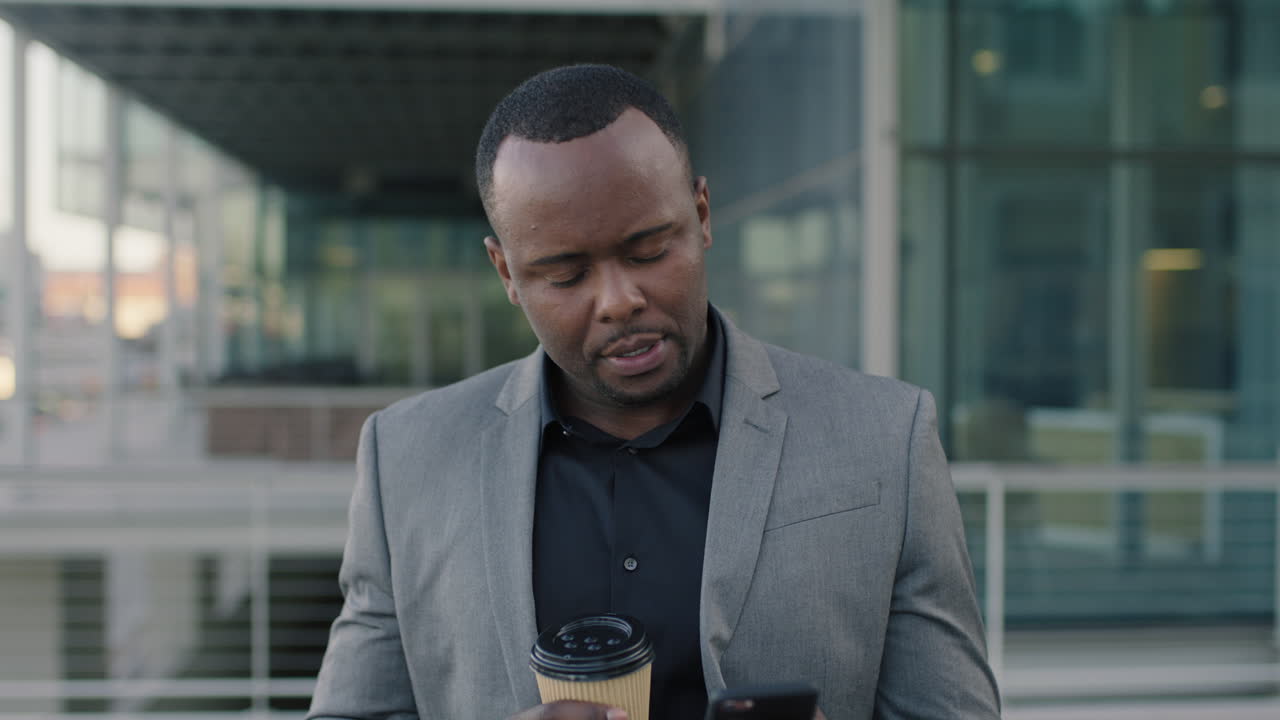 portrait of african american businessman texting using phone corporate executive holding coffee in city