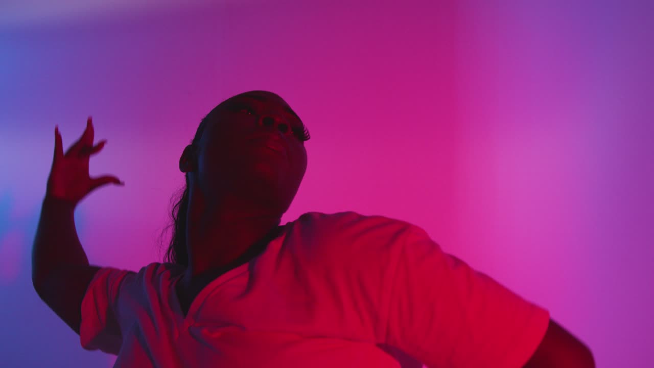 toma de estudio de una joven bailarina bailando contra un fondo iluminado de azul y rosa 2