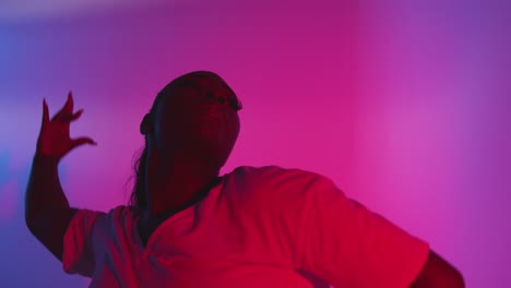 studio shot of young woman dancer dancing against blue and pink lit background 2