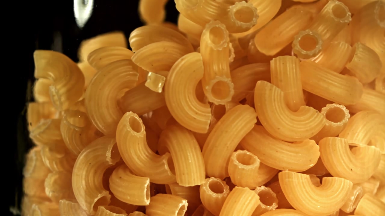Primo piano al rallentatore di maccheroni secchi che cadono