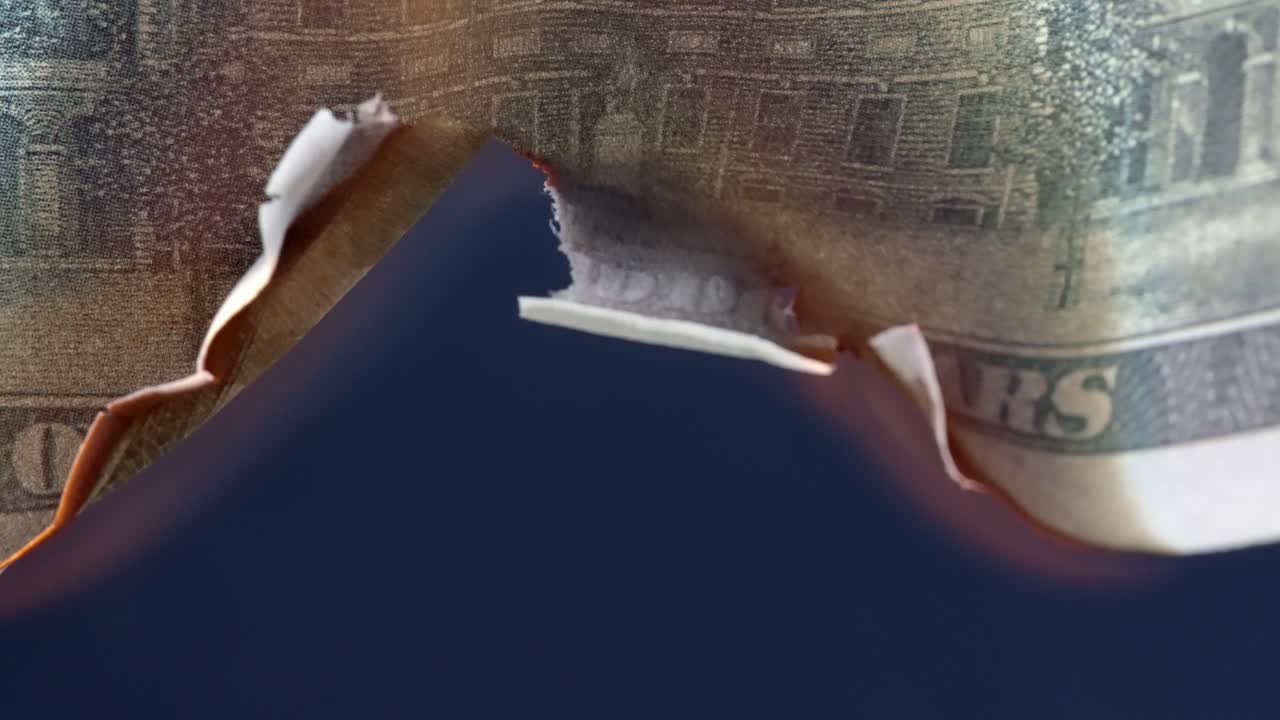 Flame burns through the center of a USA 100 dollar bill, economy collapse concept