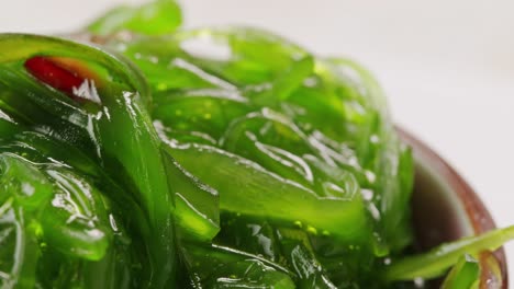 japanese wakame chuka fermented food. close-up on a detail of hiyashi wakame chuka or seaweed salad or seaweed with sesame seeds on a plate. top view. seafood background. health concept.