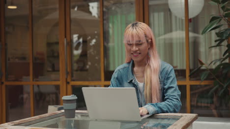 mujer trabajando en una computadora portátil en un café
