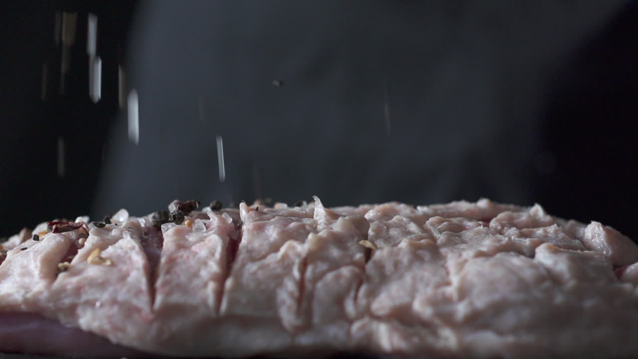 tasty duck gets seasoned on dark backdrop in slowmotion