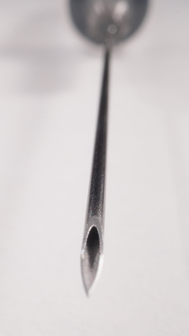 Edge of sterile syringe needle lying on white background macro view. Medical research in medical laboratory. Disposable tool for vaccination