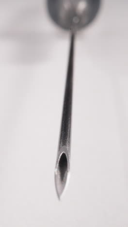 edge of sterile syringe needle lying on white background macro view. medical research in medical laboratory. disposable tool for vaccination