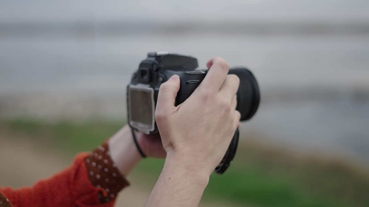 Person taking a picture with a DSLR camera outdoors