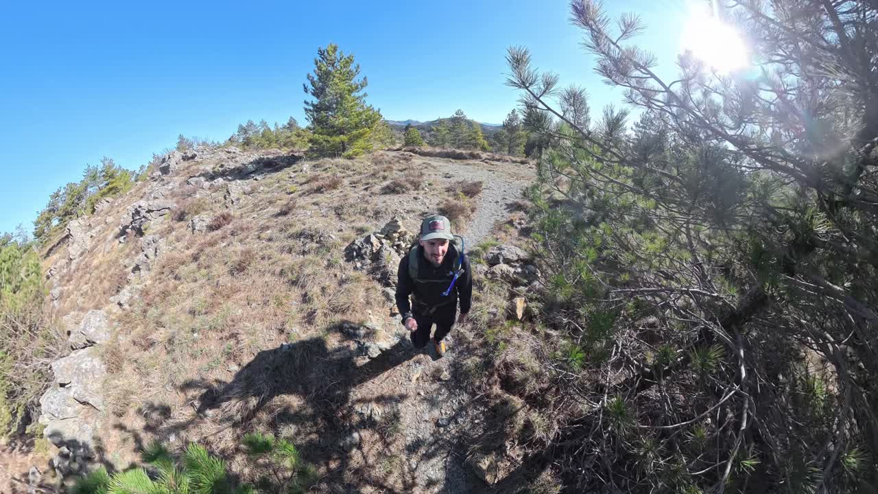 Wide angle view of young male hiker walking on a forest trail, fish-eye lens